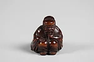Netsuke of Seated Figure of an Old Man with Backpack Containing a Mask by Unknown Artist