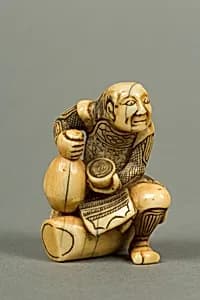 Netsuke of Man Sitting on a Log holding a Bottle and a Cup by Unknown Artist