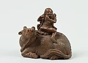 Netsuke of Man Playing Flute atop an Ox by Unknown Artist