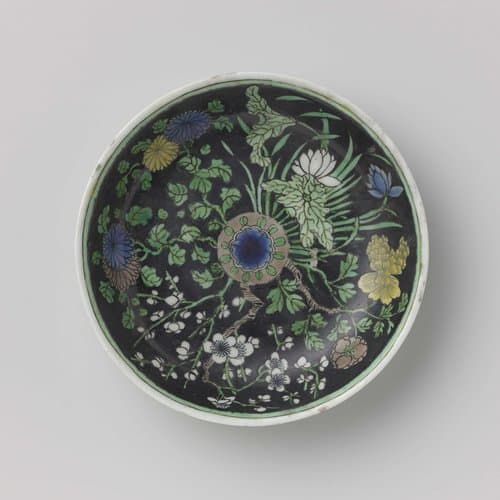 Saucer with flowering plants on a black ground by anonymous