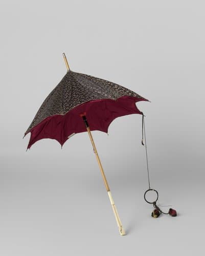 Parasol met dek van zwarte zijde met strooimotief van witte botahs en rode strepen, gevoerd met donkerrode zijde, op dunne bamboe stok met gesneden ivoren handvat en metalen punt by anonymous