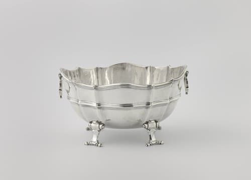 Sauskom van zilver, ovaal, op vier ingerolde pootjes. Filetranden langs de geschulpte bovenkant.