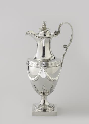 Waterkan van zilver, vaasvormig op hoge ronde voet met vierkant basement. Hoog oor in de vorm van twee ineengekronkelde slangen. Gewelfd deksel met ananas als knop. by William Garrard