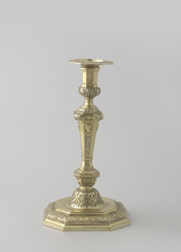 Kandelaar, deel van een paar, van verguld zilver. Versierd op de stam met trofeeën en muziekinstrumenten waarboven profielkoppen in medaillons