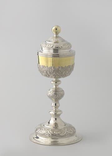 Ciborie van zilver met vergulde cuppa en dekselknop. Gewelfde voet en deksel; balusterstam. Versiering langs de randen met symmetrische rocailles op geponste grond. by Petrus van der Sanden