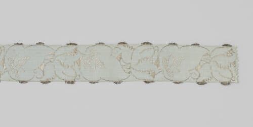 Lint van zijdebrokaat in zilver en blauw; op een lichtblauwe ondergrond is in zilver een lopende rank aangebracht by anonymous