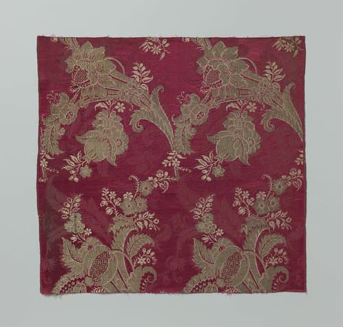 Fragment van karmijnrood damast met goudkleurig zijdeweefsel met een patroon van gestileerde bladeren en bloemen met gebogen tuilen van bloemen, bladeren en vruchten by anonymous