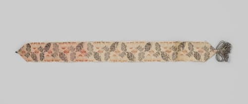 Kousenband van beige zijde met lancé-effect; de kousenband is versierd met bloemen en bladeren in zilver en oranje; met zilveren torsade by anonymous